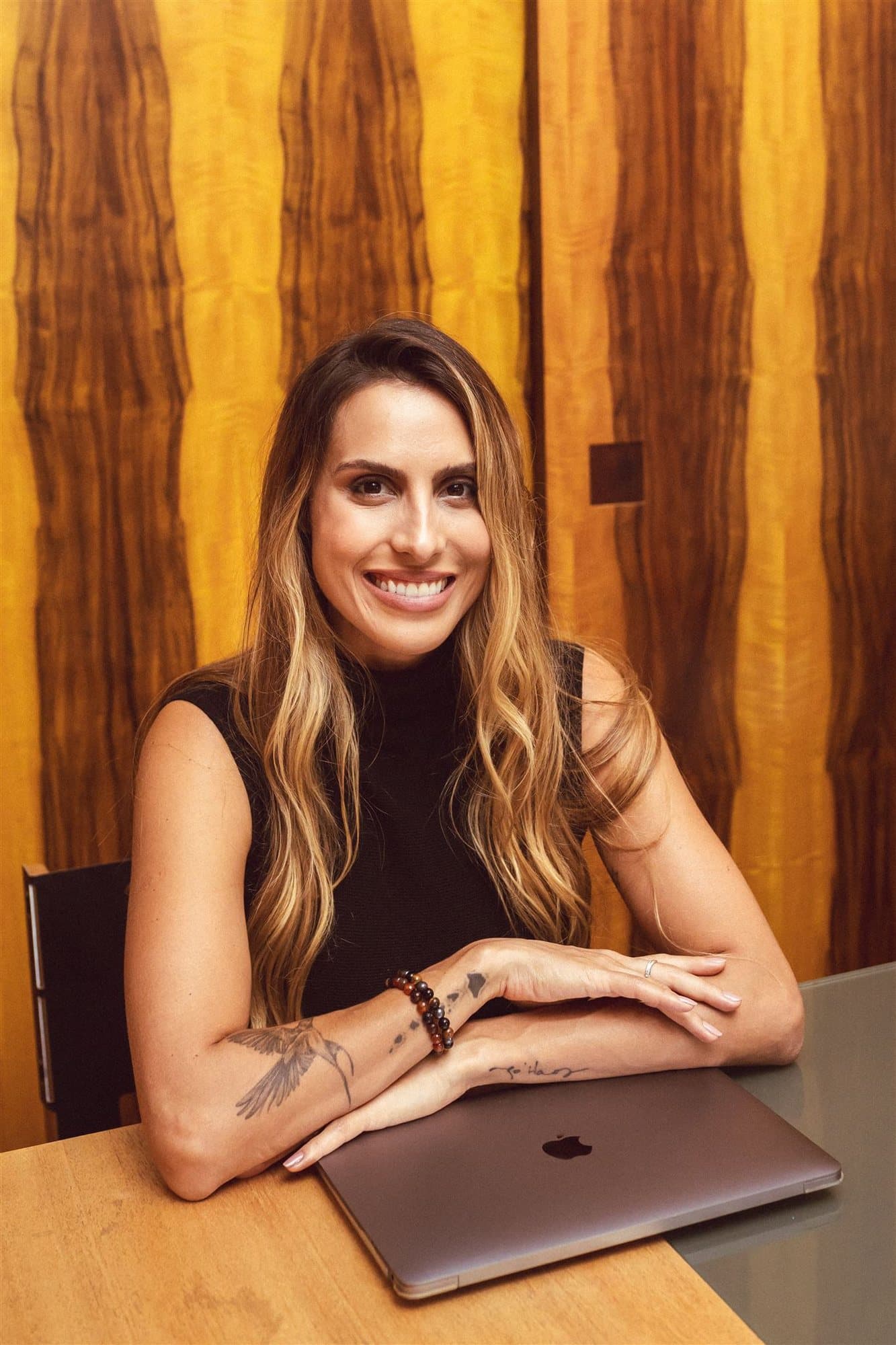 Xanda Fogaça sorrindo, sentada à mesa com um laptop